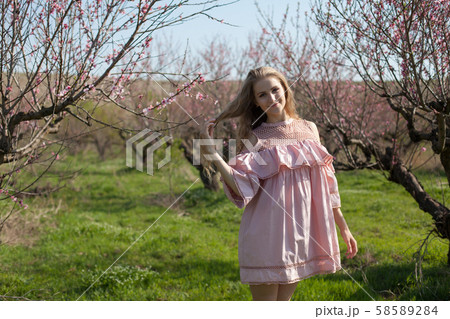Woman blonde walks in pink flowering garden Woman blonde walks in pink flowering garden 58589284