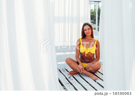 Beautiful woman with long hair in yellow swimsuit on sea beach walk 58590063