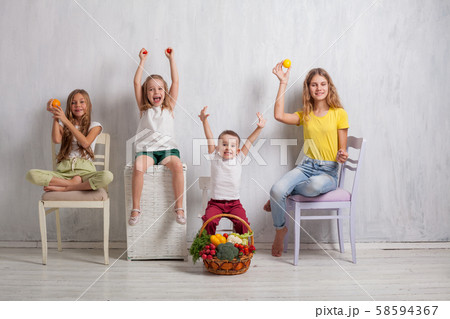 Girls and boy hold ripe vegetables and fruits Girls and boy hold ripe vegetables and fruits 58594367