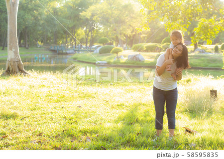 Beautiful young asian mother carrying little daughter with smile Beautiful young asian mother carrying little daughter with smile 58595835