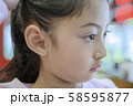 Adorable little Asian girl having ear piercing process. 58595877