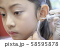 Adorable little Asian girl having ear piercing process. 58595878