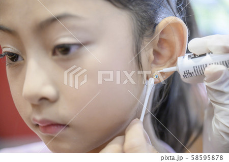 Adorable little Asian girl having ear piercing process. Adorable little Asian girl having ear piercing process. 58595878