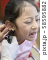 Adorable little Asian girl having ear piercing process. 58595882