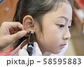 Adorable little Asian girl having ear piercing process. 58595883