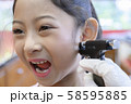 Adorable little Asian girl having ear piercing process. 58595885