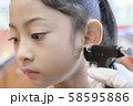 Adorable little Asian girl having ear piercing process. 58595886