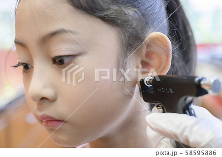 Adorable little Asian girl having ear piercing process. Adorable little Asian girl having ear piercing process. 58595886