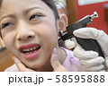 Adorable little Asian girl having ear piercing process. 58595888