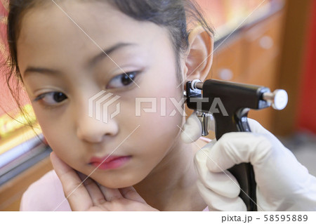 Adorable little Asian girl having ear piercing process. Adorable little Asian girl having ear piercing process. 58595889