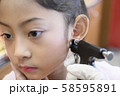 Adorable little Asian girl having ear piercing process. 58595891