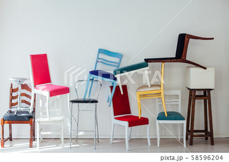 many different chairs stand in the white room 58596204