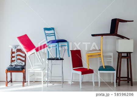 many different chairs stand in the white room 58596206