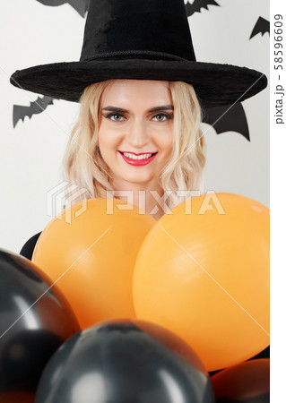 Woman in witch costume posing with balloons Woman in witch costume posing with balloons 58596609