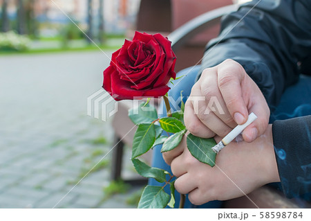 male hand with cigarette and red rose male hand with cigarette and red rose 58598784