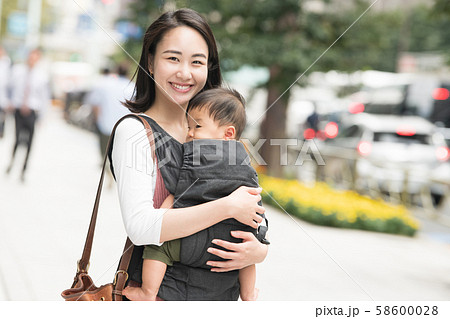 赤ちゃんと母親 親子 母子 抱っこひも 外出 買い物の写真素材