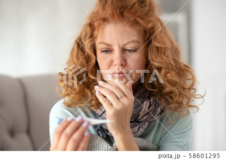 Curly woman feeling sad after seeing high temperature Curly woman feeling sad after seeing high temperature 58601295