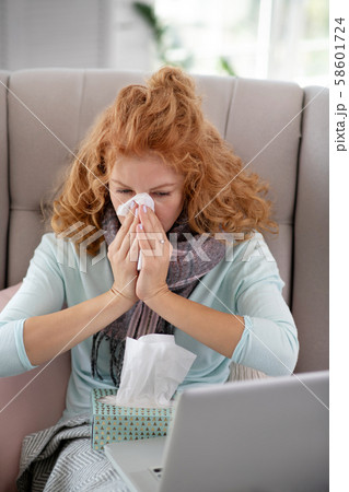 Woman having running nose while watching movie on laptop Woman having running nose while watching movie on laptop 58601724