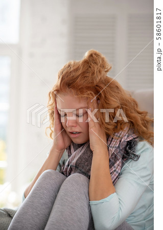 Woman wearing grey leggings touching head having awful headache Woman wearing grey leggings touching head having awful headache 58601817