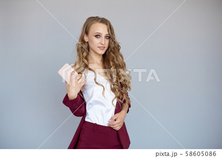 Happy young beautiful woman posing isolated on a gray wall background in a business suit holds a 58605086