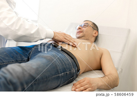 Doctor therapist probes the stomach of a male 58606459