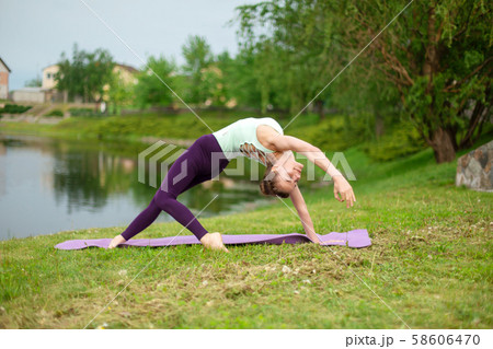 A young sports girl practices yoga on a green lawn A young sports girl practices yoga on a green lawn 58606470