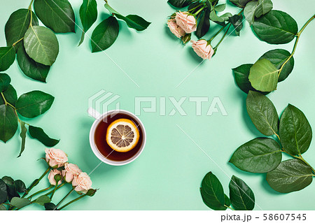 Mint background with cup of tea, marshmallows and flowers. 58607545