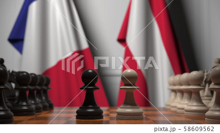Flags of France and Austria behind pawns on the chessboard. Chess game or political rivalry related Flags of France and Austria behind pawns on the chessboard. Chess game or political rivalry related 58609562