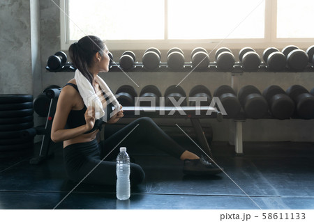 Fit young woman sitting on gym floor for relaxing 58611133