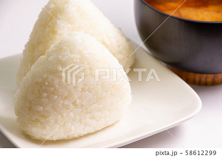 三角おにぎり(シンプルな塩むすび)2つ。写真奥にはみそ汁の入った椀。 58612299