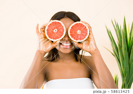 Beauty african woman with orange citrus grapefruit cover eyes with healthy skin body, isolated over 58613425