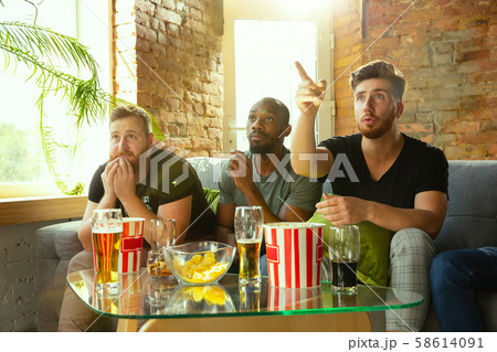 Group of friends watching football or soccer game on TV at home Group of friends watching football or soccer game on TV at home 58614091