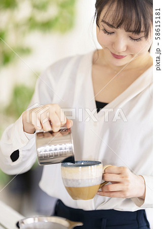陶器のコーヒーカップに注いだエスプレッソにクリーム状に泡立てたミルクを加えたカプチーノを淹れる女性 陶器のコーヒーカップに注いだエスプレッソにクリーム状に泡立てたミルクを加えたカプチーノを淹れる女性 58615181