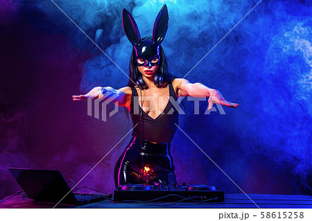 Young sexy woman dj playing music. Headphones and dj mixer on table. Young sexy woman dj playing music. Headphones and dj mixer on table. 58615258