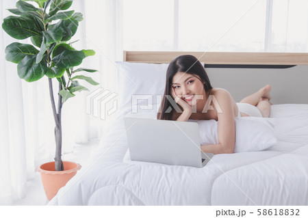 Charming woman smiles and lies on the bed with 58618832