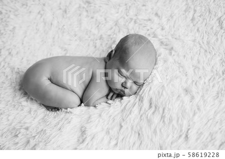 naked newborn baby lying on a white background. Imitation of a baby in the womb. beautiful little girl sleeping lying on her stomach. 58619228