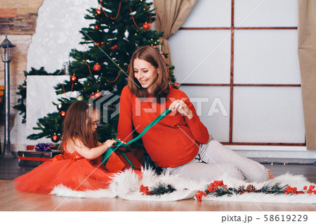 mother and daughter in red clothes unfold New year gifts under the Christmas tree. the concept of celebrating Christmas midnight 58619229