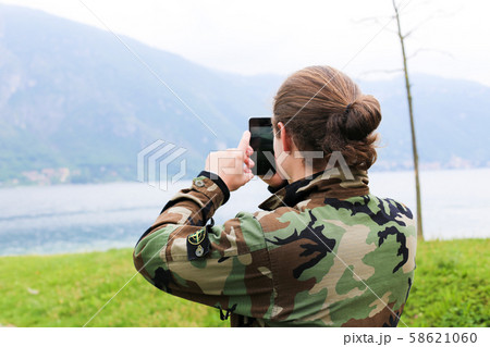 Young male tourist taking photo by smartphone, lake Como and Alps mountain in background. Young male tourist taking photo by smartphone, lake Como and Alps mountain in background. 58621060