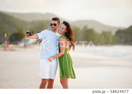 Happy couple taking a photo on white beach on honeymoon holiday 58624077