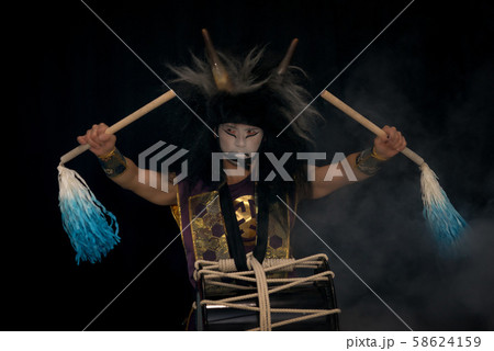 Taiko drummer in a wig and a demon mask on stage Taiko drummer in a wig and a demon mask on stage 58624159