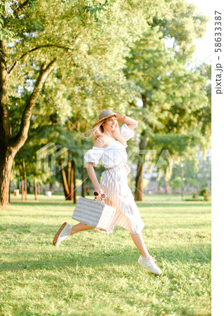 Young pretty girl jumping in park and running, wearing fashionable clothes and hat. Young pretty girl jumping in park and running, wearing fashionable clothes and hat. 58633387
