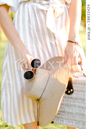 Close up bag, hat and black sunglasses in female hands. 58633424