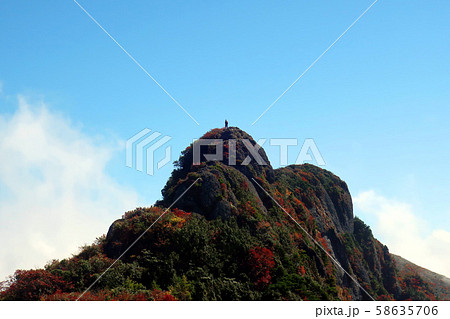 紅葉する八海山の難所、大日岳に立つ登山者 58635706