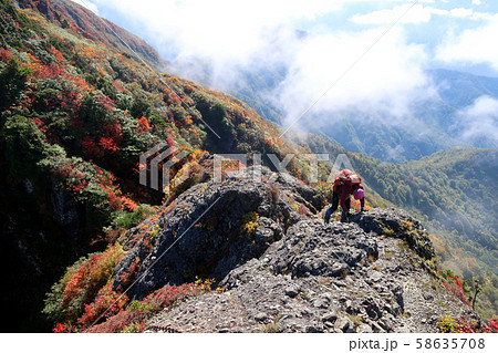 紅葉する八海山の八ツ峰を不動岳から大日岳方面へ向かう登山者 58635708