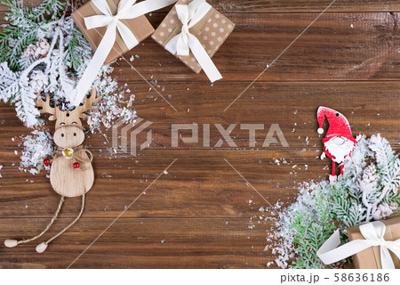 Gift boxes with fir branches, decorative toys gnome and deer with snow on a wooden background 58636186