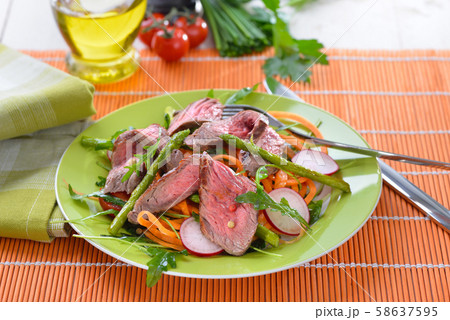 Mixed spring salad with roasted asparagus and medium fried beef steak cut into strips 58637595