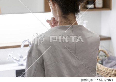 洗面室の化粧台でメイクをする若い女性の後ろ姿 58637964