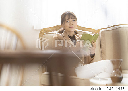 映画のワンシーンのようなおしゃれな部屋で読書を楽しみながら過ごす一人暮らしの若い女性の写真素材