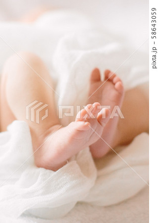 Newborn baby legs on furry cloth wearing white headband Newborn baby legs on furry cloth wearing white headband 58643059