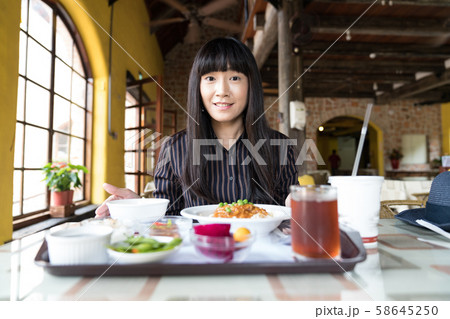 An Asian woman is by the window of the restaurant. An Asian woman is by the window of the restaurant. 58645250